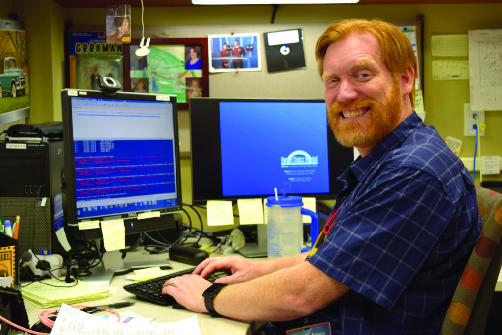 John Stinnett sitting at computer while smiling
